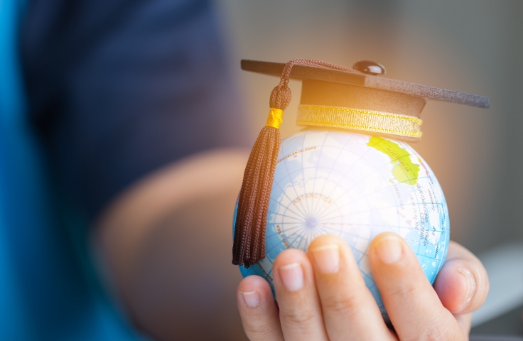 Person holding globe in hand with graduation hat